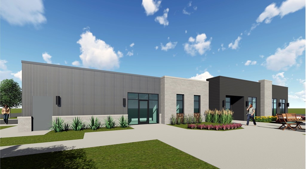 A modern building with a grey exterior and a green lawn in front.