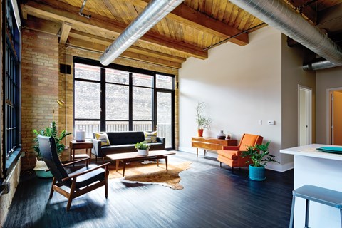 A living room with a black couch and a wooden chair.