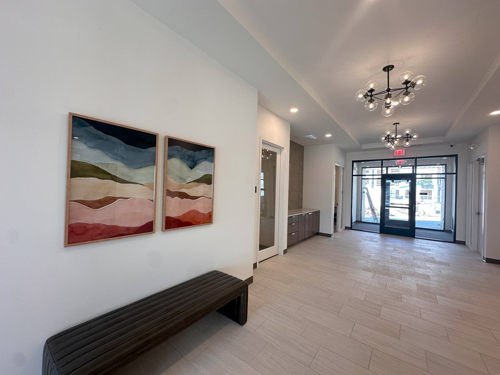 A hallway with a bench and two paintings on the wall.