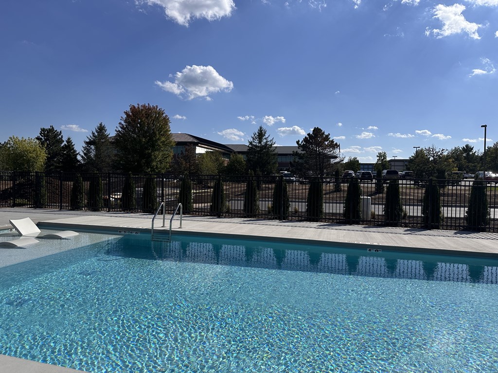 A swimming pool with a black fence and trees in the background.