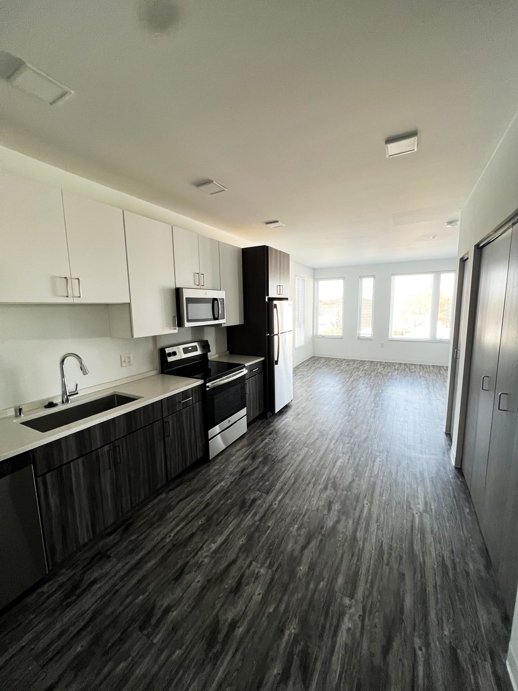 A kitchen with dark wood floors and white cabinets.