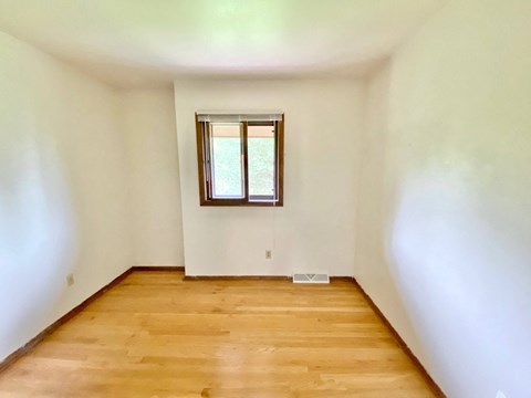 A room with a window and wooden flooring at Root River Apartments, Greendale, WI