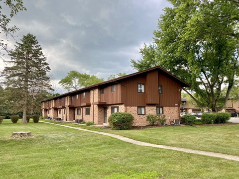 A brown building with a green lawn in front.