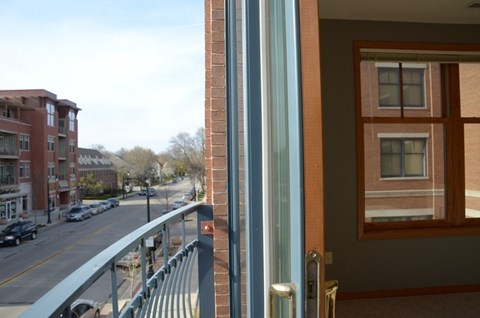 A view of a street from a window with a balcony at Cornerstone & Ravenna* Apartments, Shorewood, WI