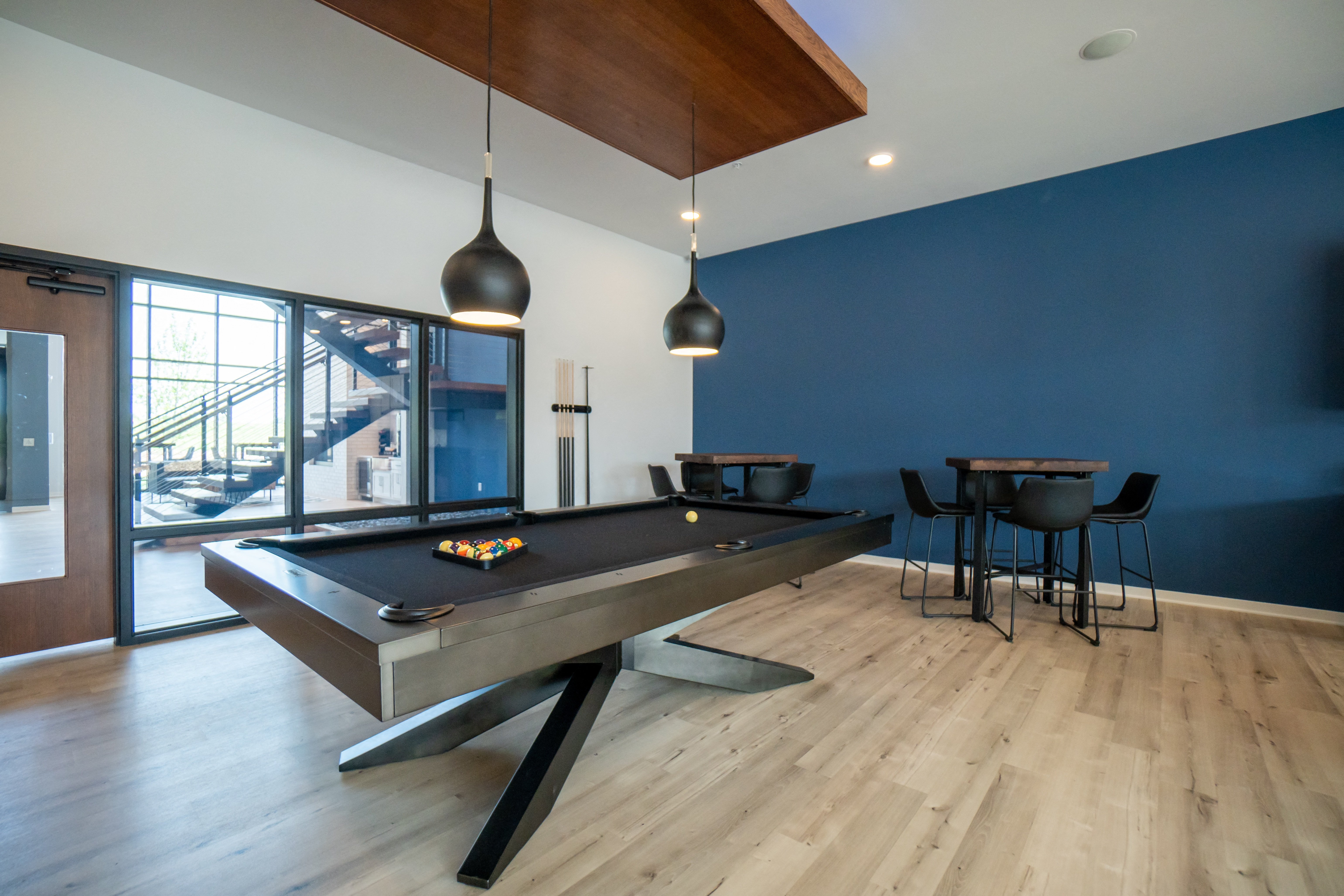 a pool table in a living room with blue walls and wood floors