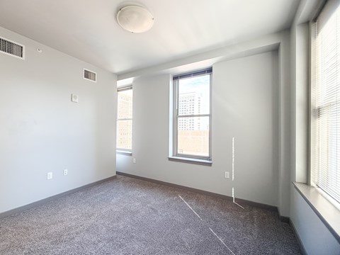 A sparsely furnished room with a window and a carpeted floor.