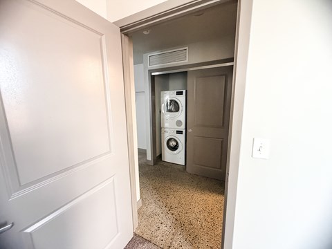 A white door opens to a small laundry room with a washer and dryer.