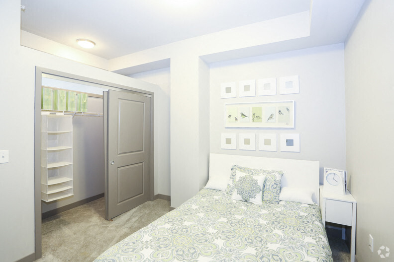 A bedroom with a bed, a nightstand, and a closet with a mirror.