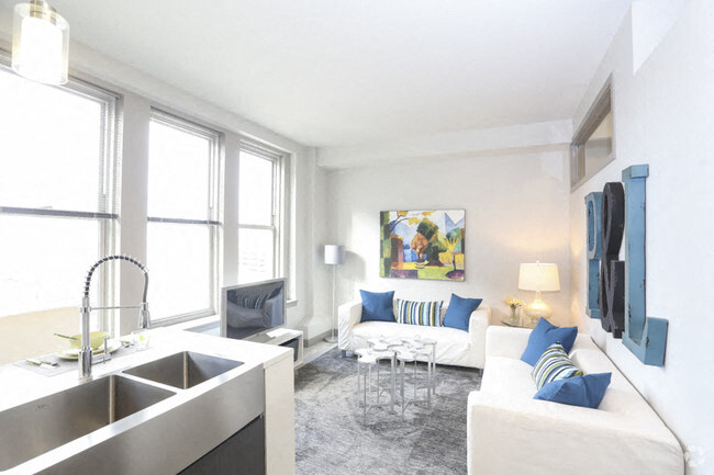 A modern kitchen with a white couch and a painting on the wall.