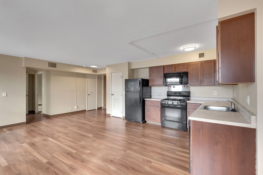 A kitchen with wooden floors and a black refrigerator.