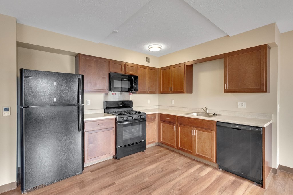 A kitchen with a black fridge, microwave, and oven.