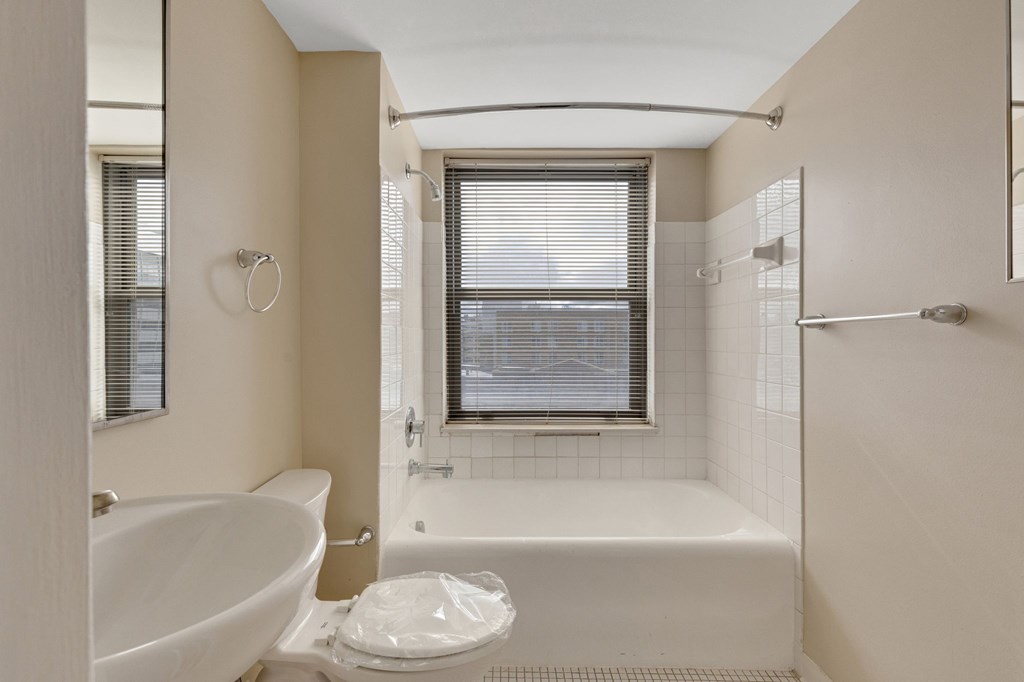 A white toilet sits in a bathroom with a white tub and sink.