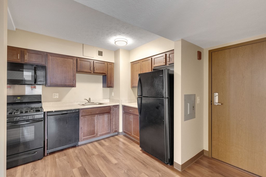 A kitchen with black appliances and wooden cabinets.