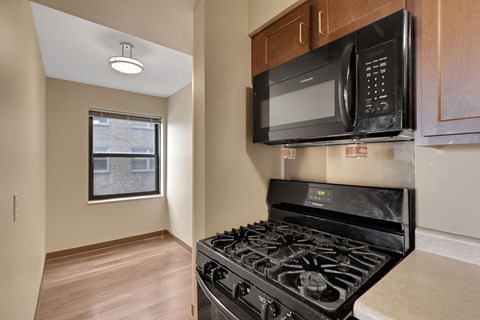 A black microwave is mounted above a black stove in a kitchen.