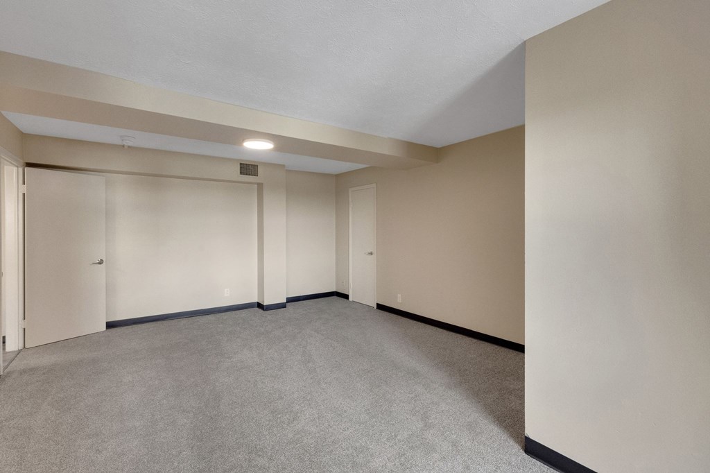 A large, empty room with carpeted flooring and white walls.