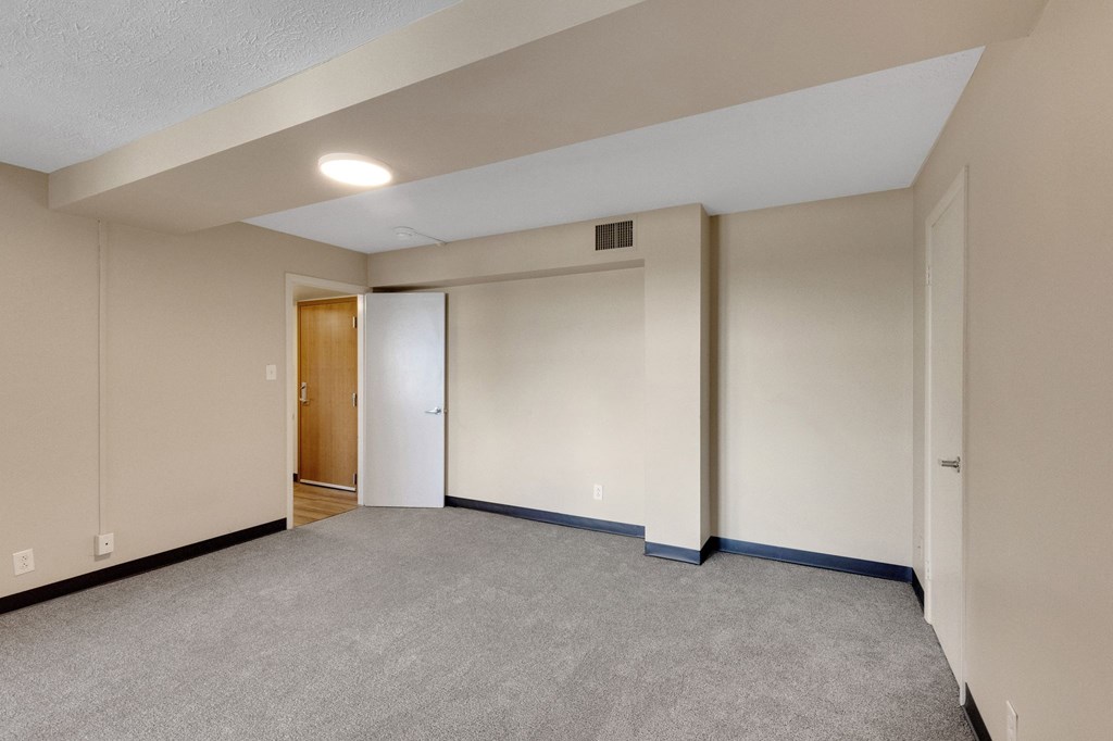 A room with a carpeted floor and a door on the left side.