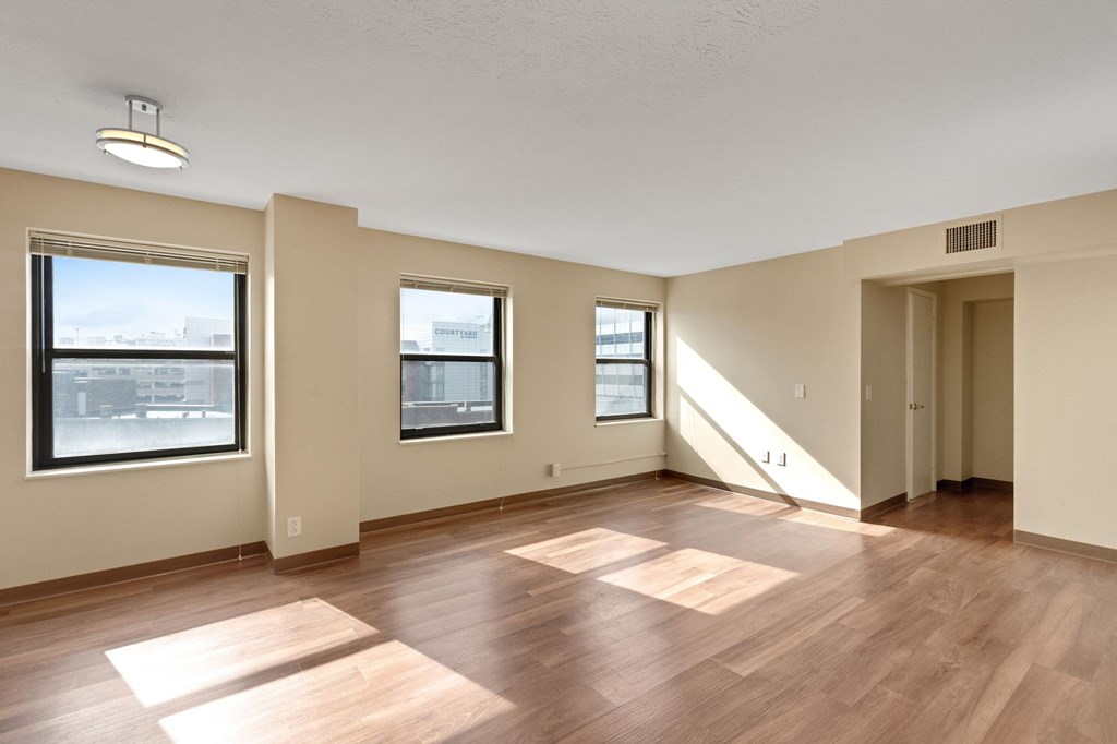 A room with wooden floors and three windows.