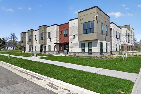 A row of modern townhouses with green lawns in front.