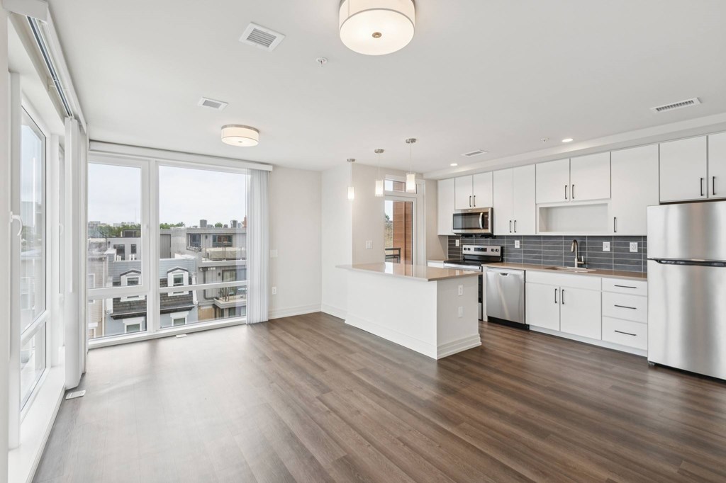 A modern kitchen with white cabinets and a wooden floor.