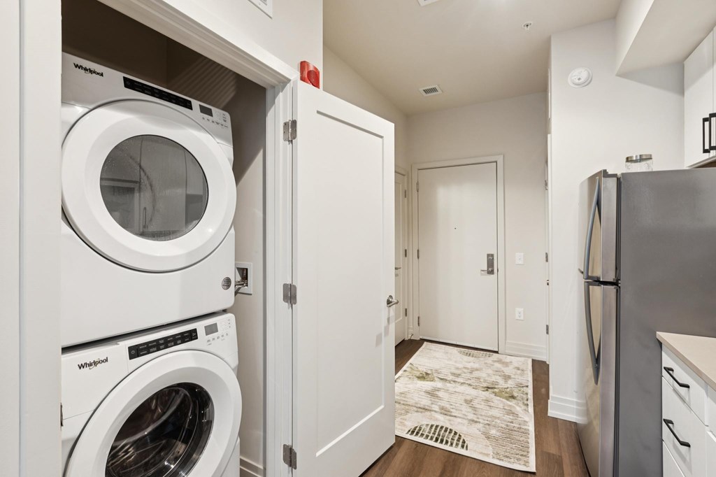 A white washing machine is in a cabinet in a small laundry room.