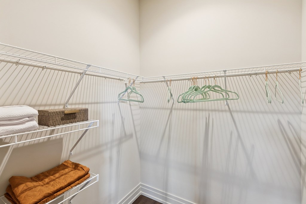 A white closet with clothes hanging on hangers.