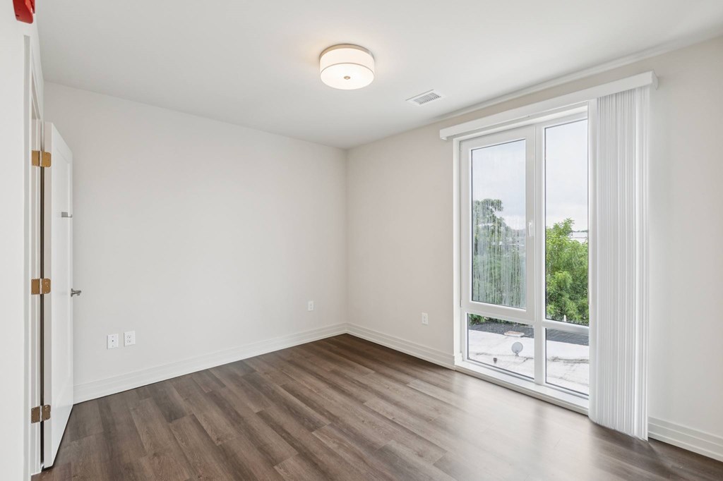 A room with a sliding glass door leading to a balcony.