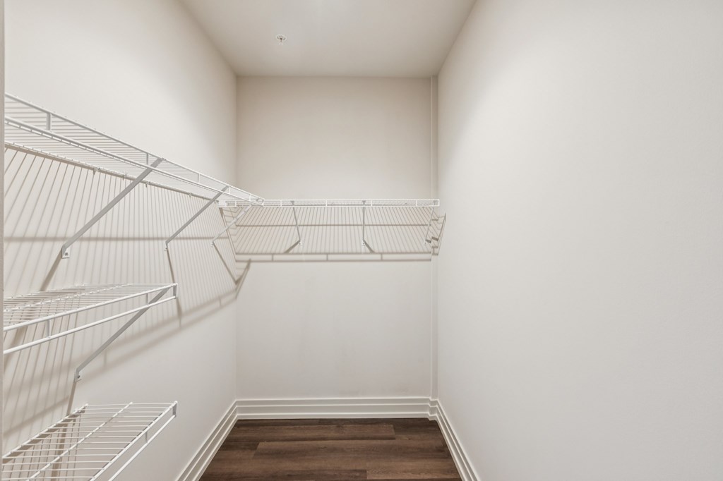 Empty white walk in closet with shelves.