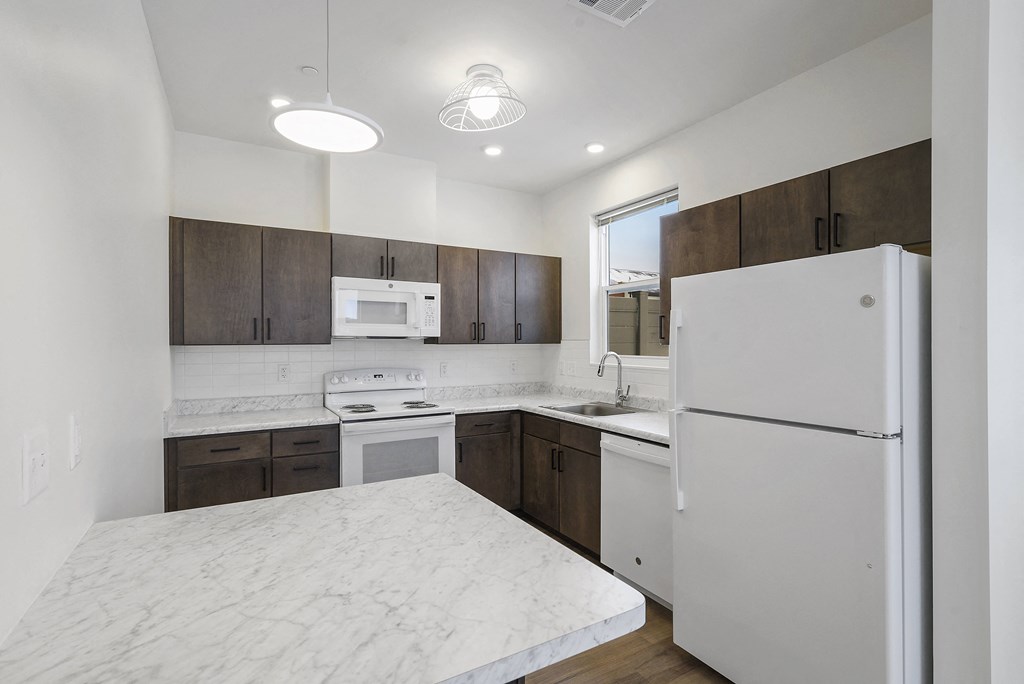 a kitchen with white marble counter tops and wooden cabinets and a refrigerator