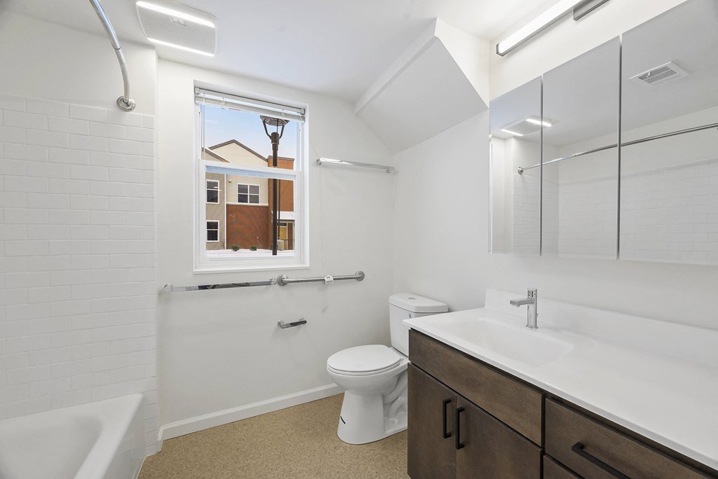 a bathroom with a toilet sink and shower and a window