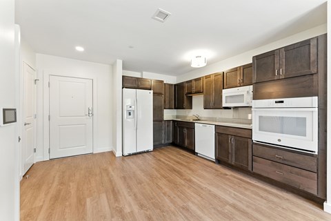 A kitchen with white appliances and brown cabinets.