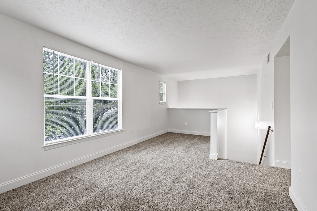 a bedroom with a large window and a carpeted floor