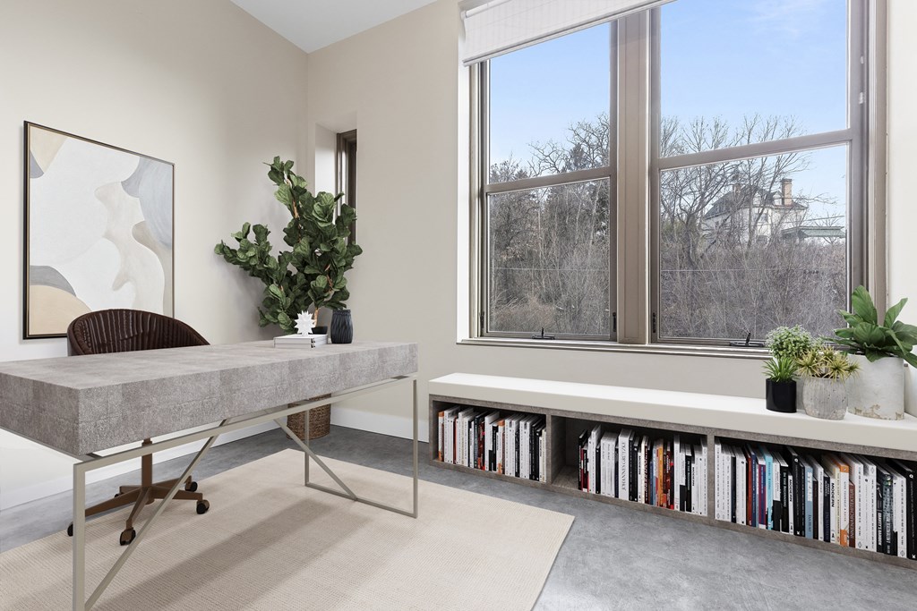 a home office with a large window and a table with bookshelves