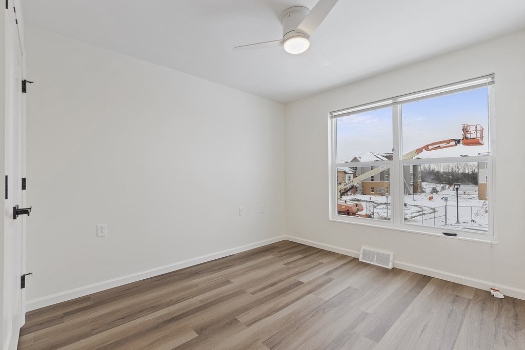 an empty living room with a large window and hardwood floors