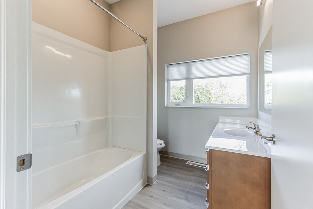 an empty bathroom with a tub and a sink and a window
