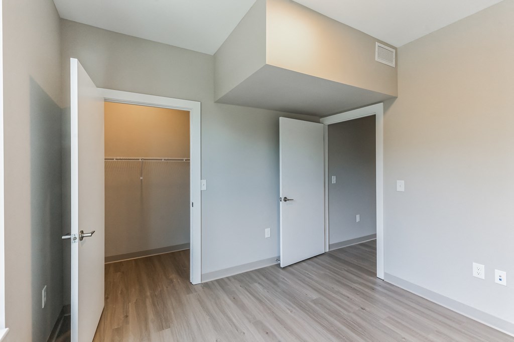 an empty room with a door to a closet and a hard wood floor