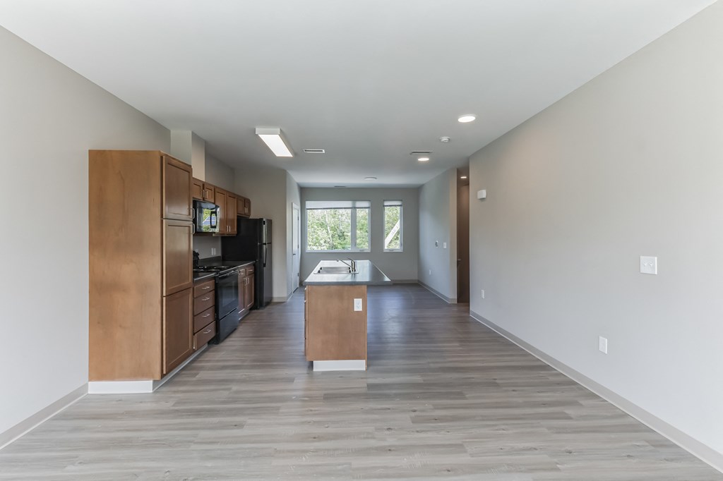 an empty living room and kitchen with wood floors and white walls