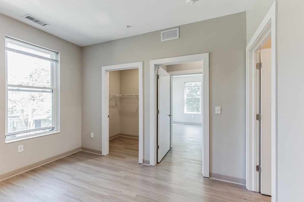 an empty bedroom and hallway with white walls and wood flooring