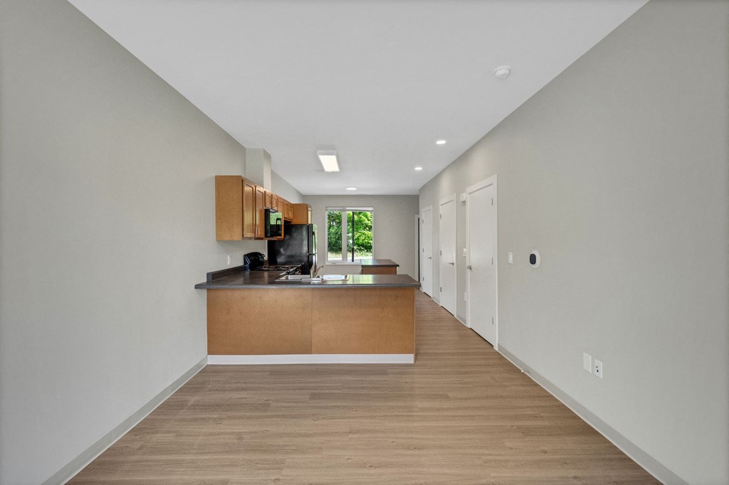 a long kitchen with white walls and wood flooring and a kitchen island with a