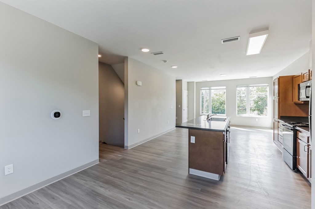 an empty kitchen and living room with white walls and wood flooring