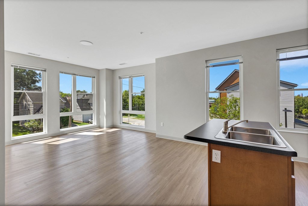 a living room with a large window and a kitchen with a sink