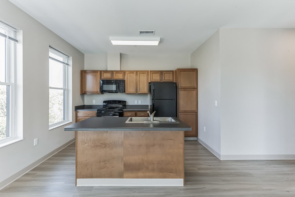 an empty kitchen with wooden cabinets and a black counter top