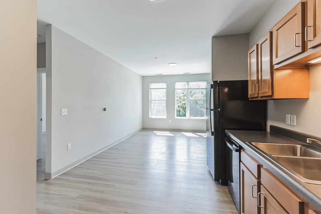 an empty kitchen and living room with wood flooring and a large window