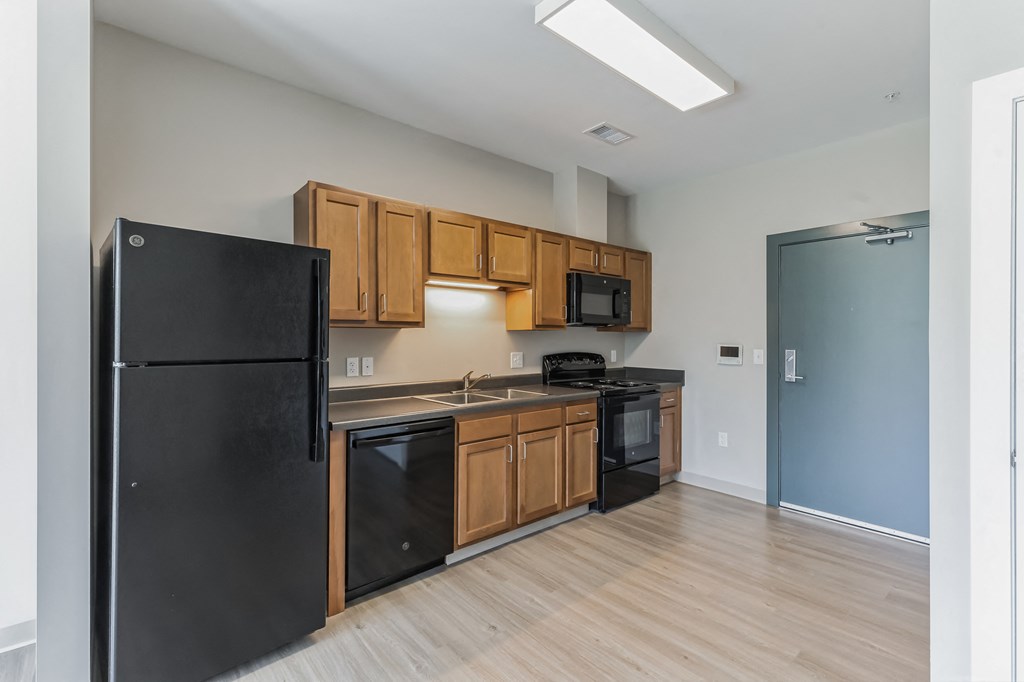 a kitchen with black appliances and wooden cabinets and a black refrigerator