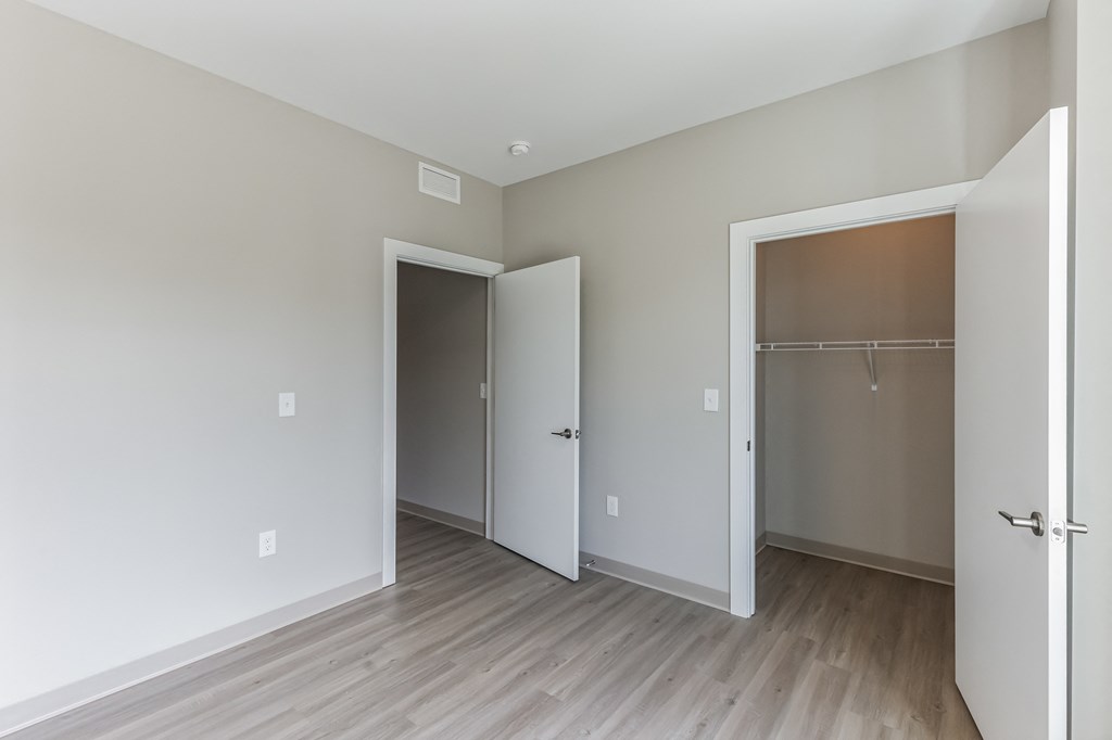 an empty room with a door to a closet and a hard wood floor