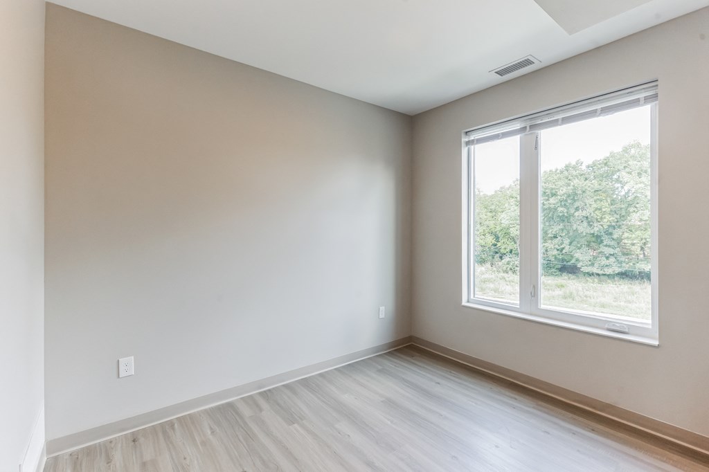 an empty room with a large window and wooden floors