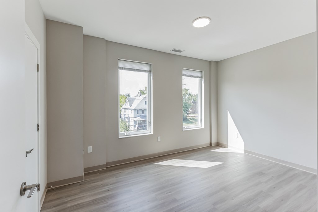an empty room with a door and two windows