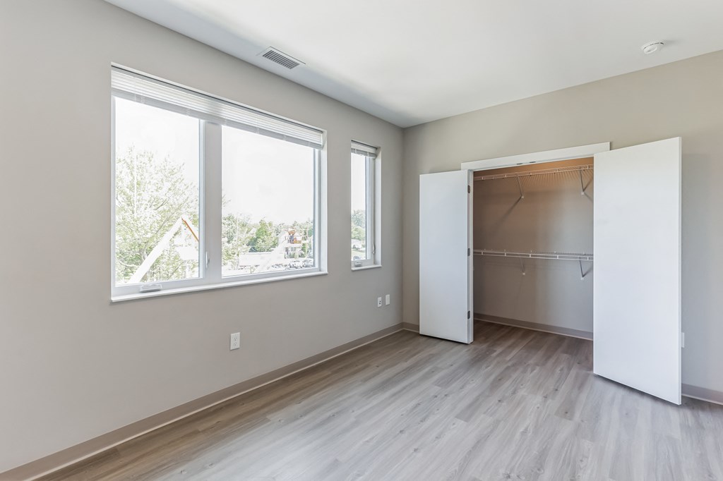 an empty room with a large window and a door to a closet