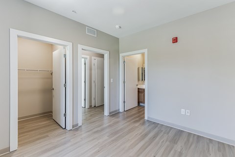 the living room and bedroom of an apartment with wood floors and white walls