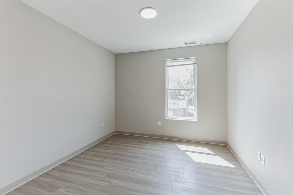 an empty room with a window and pink and purple balloons