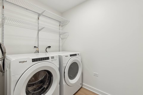 Two white Whirlpool washing machines in a laundry room.